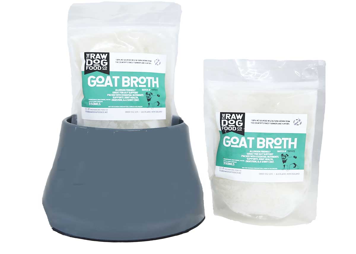 Two packets of goat bone broth supplement in a branded container, intended for pet food.