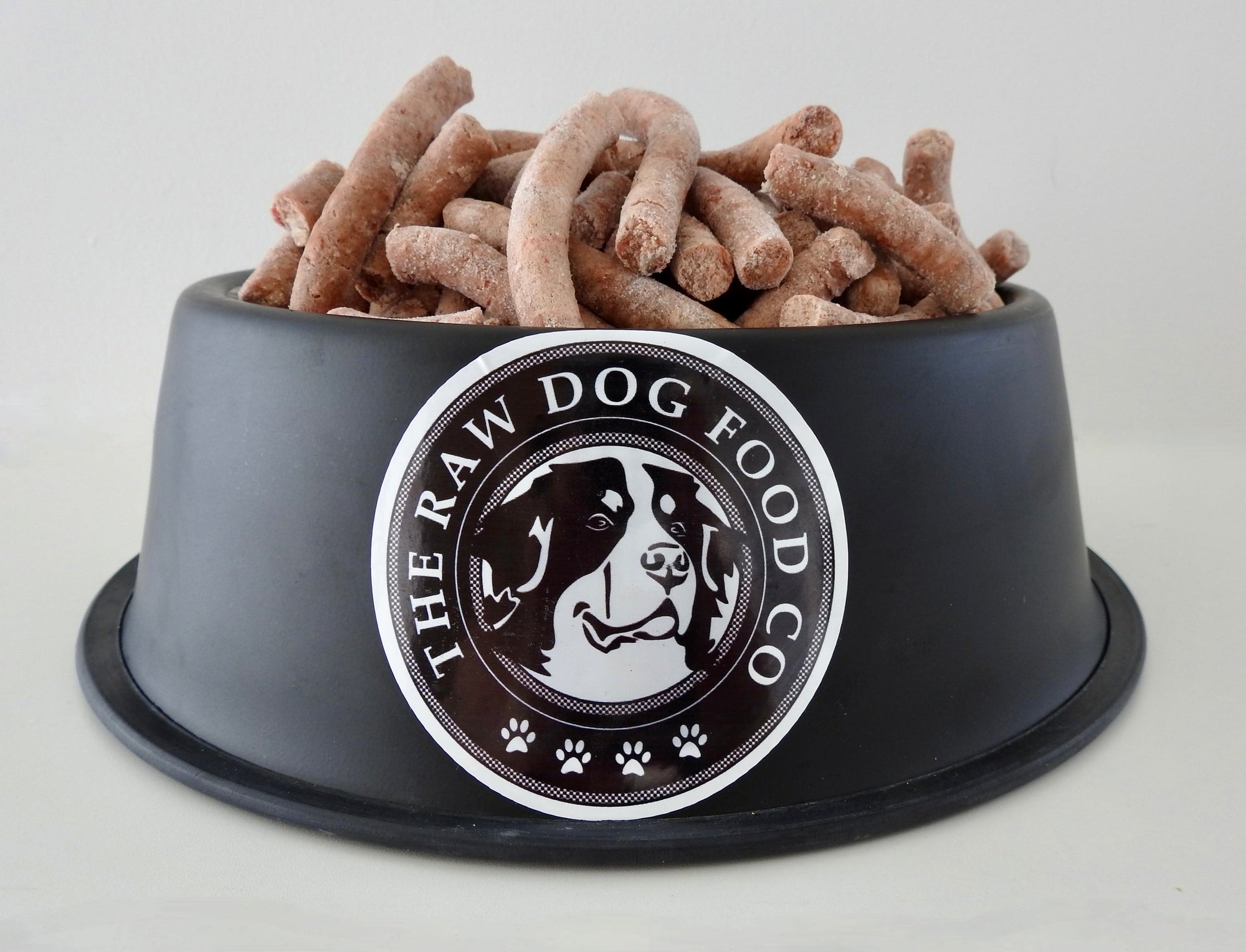 An image of a bowl of salmon and lamb frozen pet food pellets with a white background.