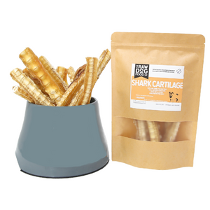 A package of air-dried shark cartilage treats for pets, next to a bowl filled with the same treats.