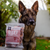 An image of a dog next to a bag of frozen beef meat for dogs. 