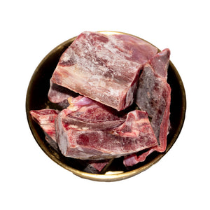 An image of a bowl of frozen goat chunks for pet food.